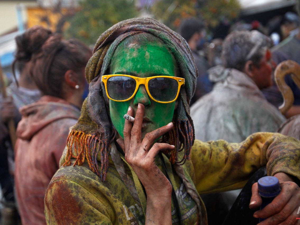A local reveler smokes a cigarette as she celebrate Clean Monday with a flour war, a unique colorful flour fight marking the end of the carnival season in the port town of Galaxidi, some 200 kilometers (120 miles) west of Athens, Monday, Feb. 23, 2015. The flour fight, on the coastal road lining Galaxidiís old harbor, takes place on Clean Monday, the beginning of the 40-day Christian Lent fast that ends on Easter Sunday. Although Clean Monday ceremonies abound across Greece, the most common being kite-flying, Galaxidiís flour-fight is unique, and is thought to have been influenced by similar goings-on in Sicily in the 19th century. (AP Photo/Petros Giannakouris)